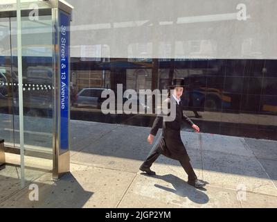 Junger orthodoxer jüdischer Mann geht entlang der 39. Street im Stadtteil Borough Park in Brooklyn, New York. Stockfoto