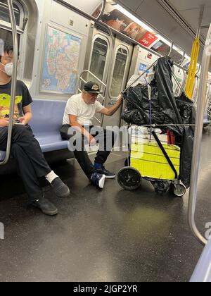 Ein müder älterer Mann mit Habseligkeiten fährt in Manhattan mit einem U-Bahn-Zug in New York City. Stockfoto
