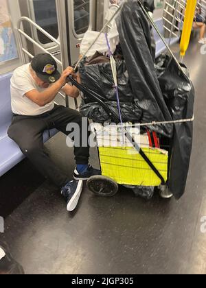 Ein müder älterer Mann mit Habseligkeiten fährt in Manhattan mit einem U-Bahn-Zug in New York City. Stockfoto