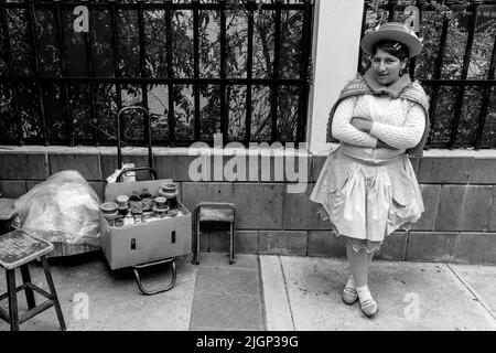 Eine junge Frau in traditionellem Kostüm, die Honig auf den Straßen von Puno, Provinz Puno, Peru verkauft. Stockfoto