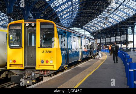 Passagiere, die in einem Zug der British Rail-Klasse 313 in der Southern Livery, Brighton Railway Station, England, einsteigen. Stockfoto