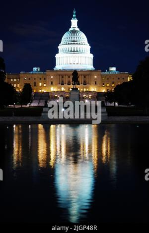 Das Kapitol der Vereinigten Staaten in Washington DC ist im ruhigen Wasser des reflektierenden Pools zu sehen und wird nachts beleuchtet Stockfoto