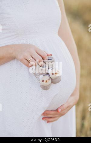 Schwangerschaft, Mutterschaft, Menschen und Erwartung Konzept - Nahaufnahme der glücklichen Schwangeren mit großem Bauch auf Natur Hintergrund. Schöne Schwangerin Stockfoto