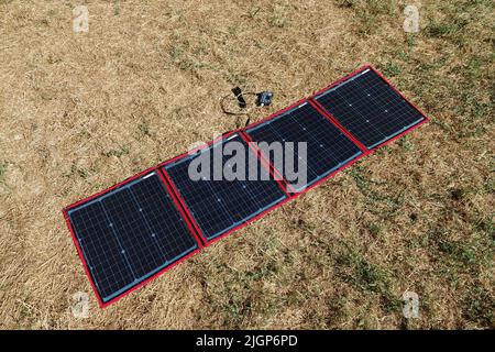 Ein faltbares, tragbares Solarpanel, das auf einem Rasen geöffnet wird Stockfoto