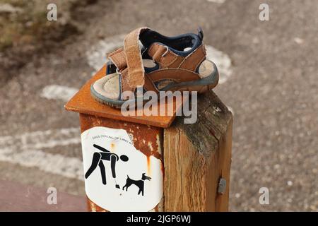 Die Sandale des verlorenen Kindes wurde auf einem Pfosten am Gehsteig aufgesetzt, damit der Besitzer sie wieder finden kann Stockfoto