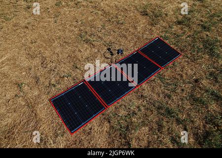 Ein faltbares, tragbares Solarpanel, das auf einem Rasen geöffnet wird Stockfoto