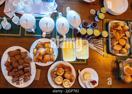 Eine Auswahl an Kuchen, Marmeladen, gerinnter Creme, Scones und Tee Stockfoto