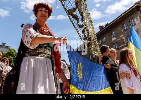 Krakau, Polen. 12.. Juli 2022. Ukrainische Frau posiert mit einer ukrainischen Flagge während einer Zeremonie, die einem Platz in der Altstadt von Krakau den Namen Unabhängige Ukraine verleiht. Die lokale Regierung betont, dass sie die Entscheidung getroffen hat, Unterstützung und Einheit mit dem ukrainischen Volk zu zeigen. Der Ort für den ukrainischen Unabhängigkeitsplatz wurde bewusst in unmittelbarer Nähe des russischen Konsulats in Krakau gewählt. Kredit: SOPA Images Limited/Alamy Live Nachrichten Stockfoto