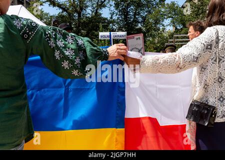 Krakau, Polen. 12.. Juli 2022. Ukrainische Frauen halten polnische und ukrainische Flaggen während einer Zeremonie, die einem Platz in der Altstadt von Krakau den Namen Unabhängige Ukraine verleiht. Die lokale Regierung betont, dass sie die Entscheidung getroffen hat, Unterstützung und Einheit mit dem ukrainischen Volk zu zeigen. Der Ort für den ukrainischen Unabhängigkeitsplatz wurde bewusst in unmittelbarer Nähe des russischen Konsulats in Krakau gewählt. Kredit: SOPA Images Limited/Alamy Live Nachrichten Stockfoto