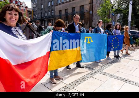 Krakau, Polen. 12.. Juli 2022. Frauen halten polnische, ukrainische und EU-Flaggen während einer Zeremonie, die einem Platz in der Altstadt von Krakau den Namen Unabhängige Ukraine verleiht. Die lokale Regierung betont, dass sie die Entscheidung getroffen hat, Unterstützung und Einheit mit dem ukrainischen Volk zu zeigen. Der Ort für den ukrainischen Unabhängigkeitsplatz wurde bewusst in unmittelbarer Nähe des russischen Konsulats in Krakau gewählt. Kredit: SOPA Images Limited/Alamy Live Nachrichten Stockfoto