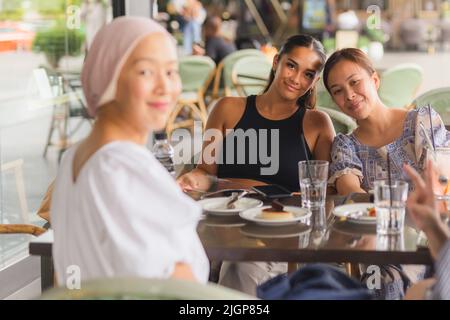 Glückliche Dame, die Kaffee und Kuchen im Café im Freien zusammen hat. Stockfoto