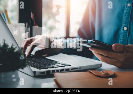 Ein Geschäftsmann, der einen Laptop mit holografischen Grafiken und Börsenstatistiken verwendet, profitiert, wächst, macht Fortschritte oder setzt ein Erfolgskonzept ein. Stockfoto