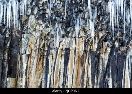 Eiszapfen aus dem Spray von Svartifoss, Island. Ein dünner, 20m-facher Wasserfall in der Mitte einer dramatischen Wand aus sechseckigen Basaltsäulen aus dem Jahr 3D. Stockfoto