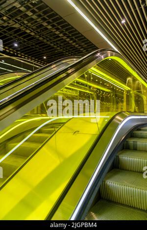 Bahnhofsebene des Bahnhofs Canary Wharf an der neuen Elizabeth Line U-Bahn in London. Rolltreppen sind in gelbes Glas gehüllt. Stockfoto
