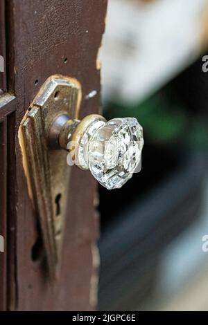Nahaufnahme eines antiken Türknopfes aus klarem Glas an einem alten Türschloss mit Skelett-Schlüsselloch. Stockfoto