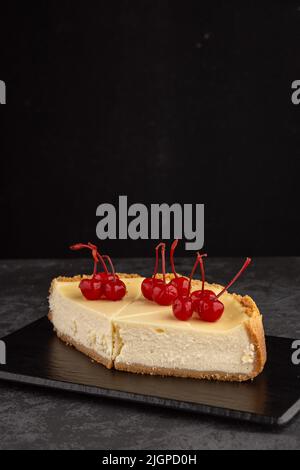 Klassischer Käsekuchen mit Kirschen auf dunklem Hintergrund. Stockfoto