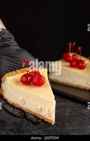 Klassischer Käsekuchen mit Kirschen auf dunklem Hintergrund. Stockfoto