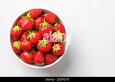 Frische Erdbeeren in einer weißen Schüssel auf grauem Hintergrund. Stockfoto