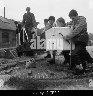 1960s, historisch, Jugendliche, die ein Holztor schieben, um die Schleuse an einem Kanal zu öffnen, England, Großbritannien. Ein Schloss ist ein wasserdichtes Becken und Tore an jedem Ende der Schleusenkammer ermöglichen es den Booten ein- und auszufahren. Torschlösser stammen aus dem 10.. Jahrhundert und dem Großen Kanal Chinas. Stockfoto