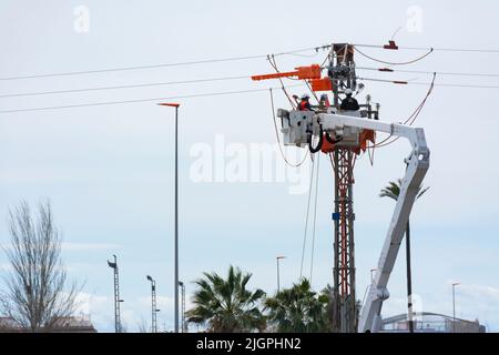 Zwei nicht erkennbare Arbeiter in einem hydraulischen Hubkorb, die Wartungsarbeiten an einer Stromleitung durchführen. Speicherplatz kopieren Stockfoto