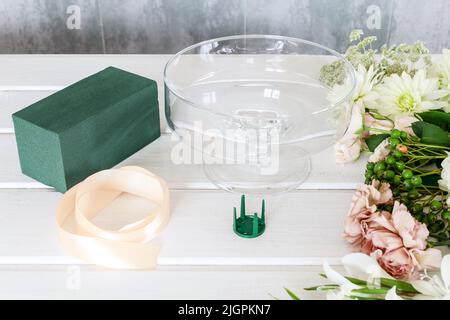 Blumenhändler bei der Arbeit. Wie Blumenschmuck für Sommerparty Tisch zu machen. Mittelstück mit Rosen-, Dahlia- und Hortensienblüten. Schritt für Schritt, diy. Stockfoto