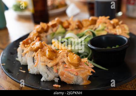 Sushi-Rollteller mit panierter Garnele und Sauce darauf. Traditionelles japanisches Essen im mexikanischen Stil Stockfoto