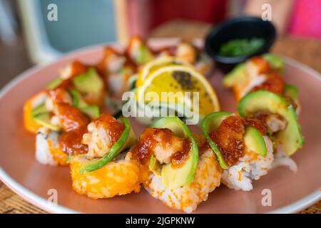 Kalifornischer Sushi-Rollteller mit Avocado, Garnelen und würziger Sauce darauf. Gourmet Food Restaurant Konzept Stockfoto