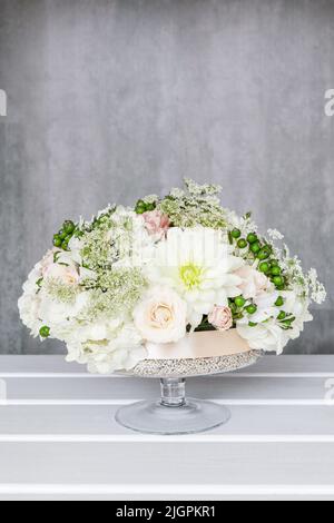 Blumenhändler bei der Arbeit. Wie Blumenschmuck für Sommerparty Tisch zu machen. Mittelstück mit Rosen-, Dahlia- und Hortensienblüten. Schritt für Schritt, diy. Stockfoto