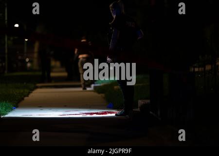 Chicago, USA. 17.. Juni 2022. Ein Polizeibeamter strahlt eine Taschenlampe über das, was am 17. Juni 2022 bei einem Mordgeschehen in Chicago, IL, Blut zu sein scheint. (Foto: Daniel Brown/Sipa USA) Quelle: SIPA USA/Alamy Live News Stockfoto