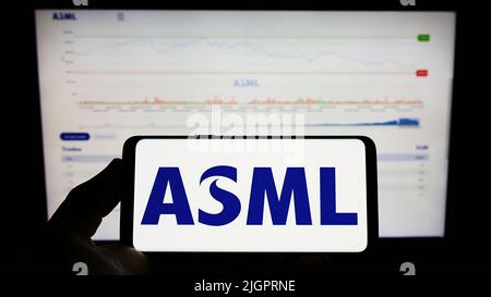 Person mit Mobiltelefon und Logo des niederländischen Halbleiterunternehmens ASML Holding N.V. auf dem Bildschirm vor der Webseite. Konzentrieren Sie sich auf die Telefonanzeige. Stockfoto