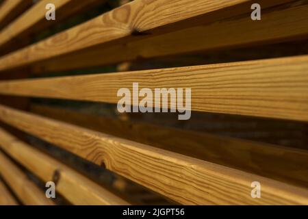 Seitenansicht einer Wand aus braunen Holzbalken in einem Pavillon in der Natur. Die Schönheit der Geometrie. Abstrakter Holzhintergrund. Das natürliche Holzbaumaterial für die Veredelung. Material mit Holzstruktur. Stockfoto