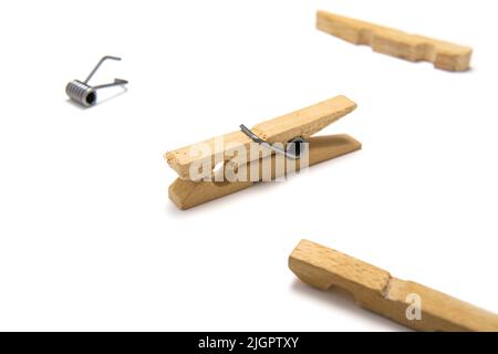 Hölzerne Wäscheklammer isoliert auf weißem Hintergrund, umgeben von einer anderen Kleidernadel, zerlegt in Stücke. Nahaufnahme. Stockfoto
