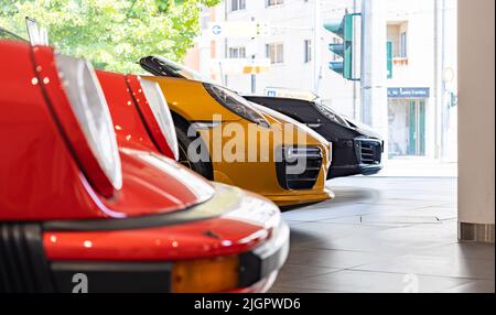 Ein Bild von der Vorderseite von drei verschiedenen Porsches, mit einem orangefarbenen Porsche 911 Turbo S in der Mitte. Stockfoto