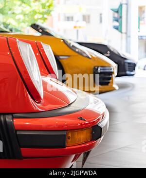 Ein Bild von der Vorderseite von drei verschiedenen Porsches, mit einem roten Porsche 911 Carrera 3,0 im Vordergrund. Stockfoto