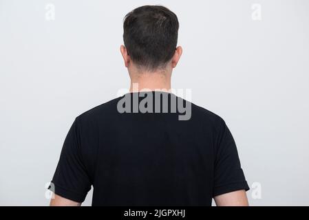Rückansicht des Mannes mit schwarzem T-Shirt auf weißem Hintergrund. Speicherplatz kopieren. Stockfoto