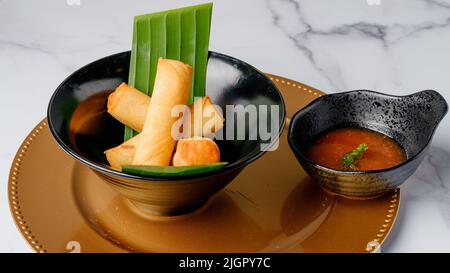 Knusprige vegetarische Brötchen. Traditionelles chinesisches Thai-Restaurant, Vorspeise, Frühlingsrollen gefüllt mit chinesischem Gemüse, Nahaufnahme auf einem Teller, der mit Chili d serviert wird Stockfoto