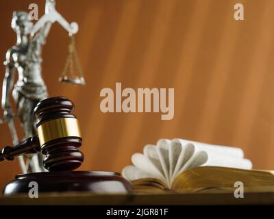 Auf beigem Hintergrund ein Holzgavel eines Richters, ein offenes Buch und eine Figur von Themis, der Göttin der Gerechtigkeit. Faires Verfahren, Demokratie, Rechtsstaatlichkeit, c Stockfoto