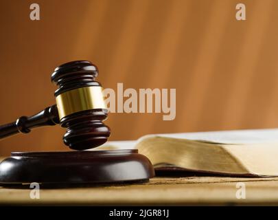 Nahaufnahme. Auf dem Tisch steht ein offenes Buch und ein Holzgavel eines Richters. Symbole eines fairen Prozesses. Rechtsstaatlichkeit, Verfassung, Demokratie. Banner, Poster. Weitere Stockfoto