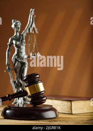 Symbole der Gerechtigkeit - ein hölzerner Gavel eines Richters, eine Figur von Themis und ein offenes Buch auf beigefarbenem Hintergrund. Gericht und Justiz, Verfassung, Herrschaft von Stockfoto