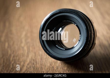 Nahaufnahme eines Kameraobjektivs, das auf einem braunen Holztisch platziert ist Stockfoto