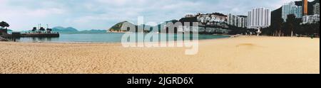 Eine Panoramaaufnahme des Sandstrandes an der Repulse Bucht mit Gebäuden und Wolkenkratzern im Hintergrund Stockfoto
