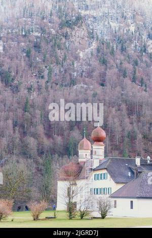 Eine vertikale Aufnahme der Bartholomäus-Kirche mit Bergwald im Hintergrund in Deutschland Stockfoto