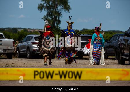 Kahnawake, Kanada. 10.. Juli 2022. Drei Pow-Wow-Teilnehmer, die zwischen den Aufführungen eine Pause einlegen. Die jährlichen Echoes of a Proud Nation Pow-Wow 30. brachten Tausende von Menschen aus ganz Nordamerika ein, um die Kultur und Traditionen der Ureinwohner im Mohawk Reserve von Kahnawake zu feiern. Nach einer zweijährigen Pause bot der größte Pow-Wow in Quebec eine Zeit zum Treffen, Tanzen, Singen, Besuchen und Feiern mit Freunden und Familie. Kredit: SOPA Images Limited/Alamy Live Nachrichten Stockfoto