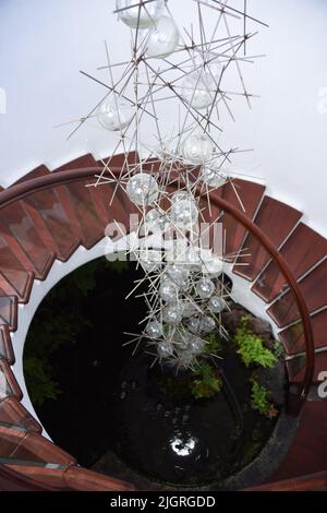 Eine vertikale Aufnahme einer Innenansicht eines Gebäudes mit Holztreppen und einer in der Luft hängenden Lampe Stockfoto