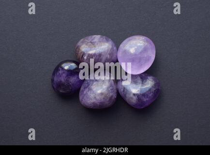 Edelsteinmineralien auf schwarzem Hintergrund. Rund taumelnde Mineralien aus Amethyst und Amethyst-Kristall. Stockfoto