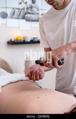 Professioneller Therapeut bereitet sich auf eine traditionelle Thai-entspannende Rückenmassage vor. Tiefe Gewebetechnik mit Öl. Aromatherapie. Stockfoto