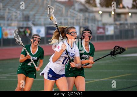 High School Mädchen spielen ein temperamentvoll gelassenes Lacrosse Spiel in einem Downey, CA, Stadion. Beachten Sie die Vision verbessernde Gesichtsfarbe. Stockfoto