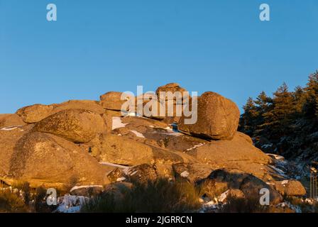 Satz von Granitsteinen bei Sonnenuntergang mit blauem Himmel und Schnee im Frühjahr Extremadura Stockfoto