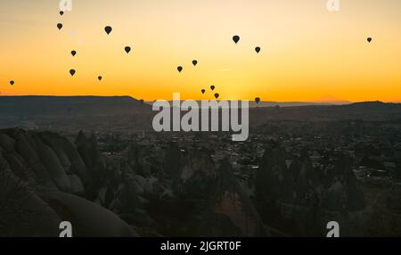Am frühen Morgen im Tal mit Felsen und Luftballons am Himmel in der Dämmerung. Kappadokien. Türkei.Selektiver Fokus auf Luftballons am Himmel. Stockfoto