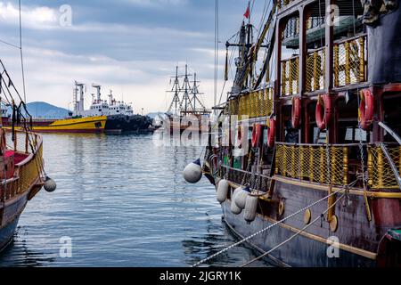 Schiffe und Vergnügungsyachten liegen am Seebrücke. Wunderschöne Partyschiffe und Schlepper stehen auf dem Pier im Meer. Stockfoto